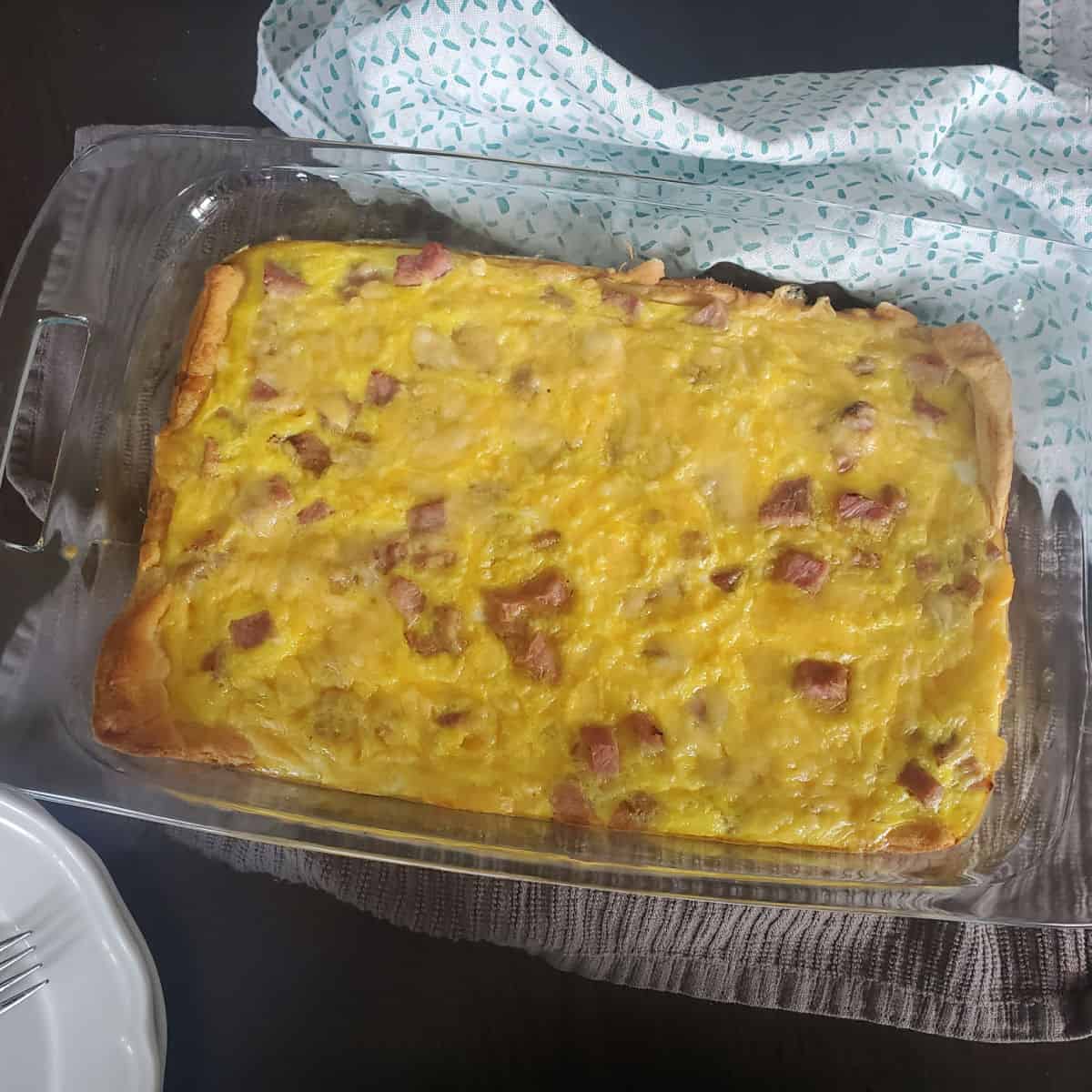 ham, cheese, and egg baked on a crescent roll in a glass casserole dish