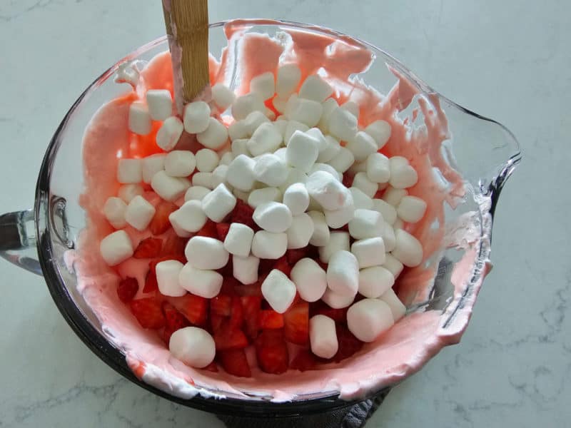 Mini marshmallows and strawberries on top of strawberry fluff in a glass bowl