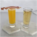 Irish Breakfast Shot with orange juice in a shot glass topped with a slice of bacon, and Jameson in a 2nd shot glass