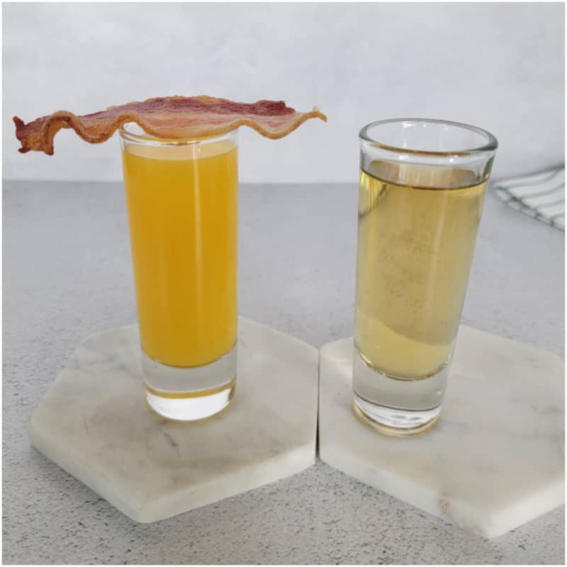 Irish Breakfast Shot with orange juice in a shot glass topped with a slice of bacon, and Jameson in a 2nd shot glass