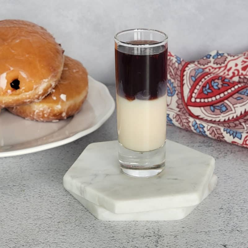 Layered Jelly Donut shot next to a jelly doughnut and napkin