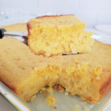 Square of Cornbread on a serving spoon over a dish of cornbread