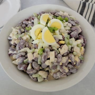 Kidney Bean Salad with hard boiled egg pieces on top in a white bowl