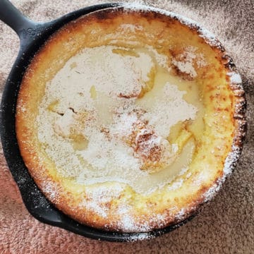 Lemon Dutch baby with powdered sugar in a cast iron skillet