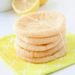Lemon sugar cookies in a stack wrapped in twine on a yellow napkin with lemons in the background