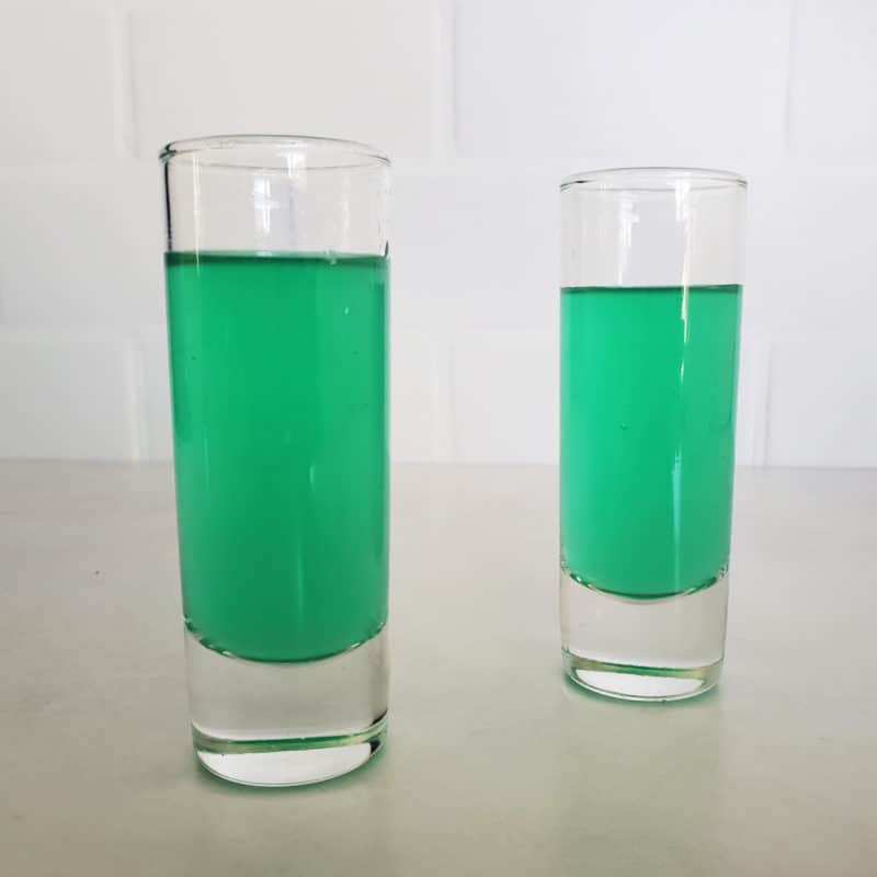 Two green cocktail shots in tall shot glasses
