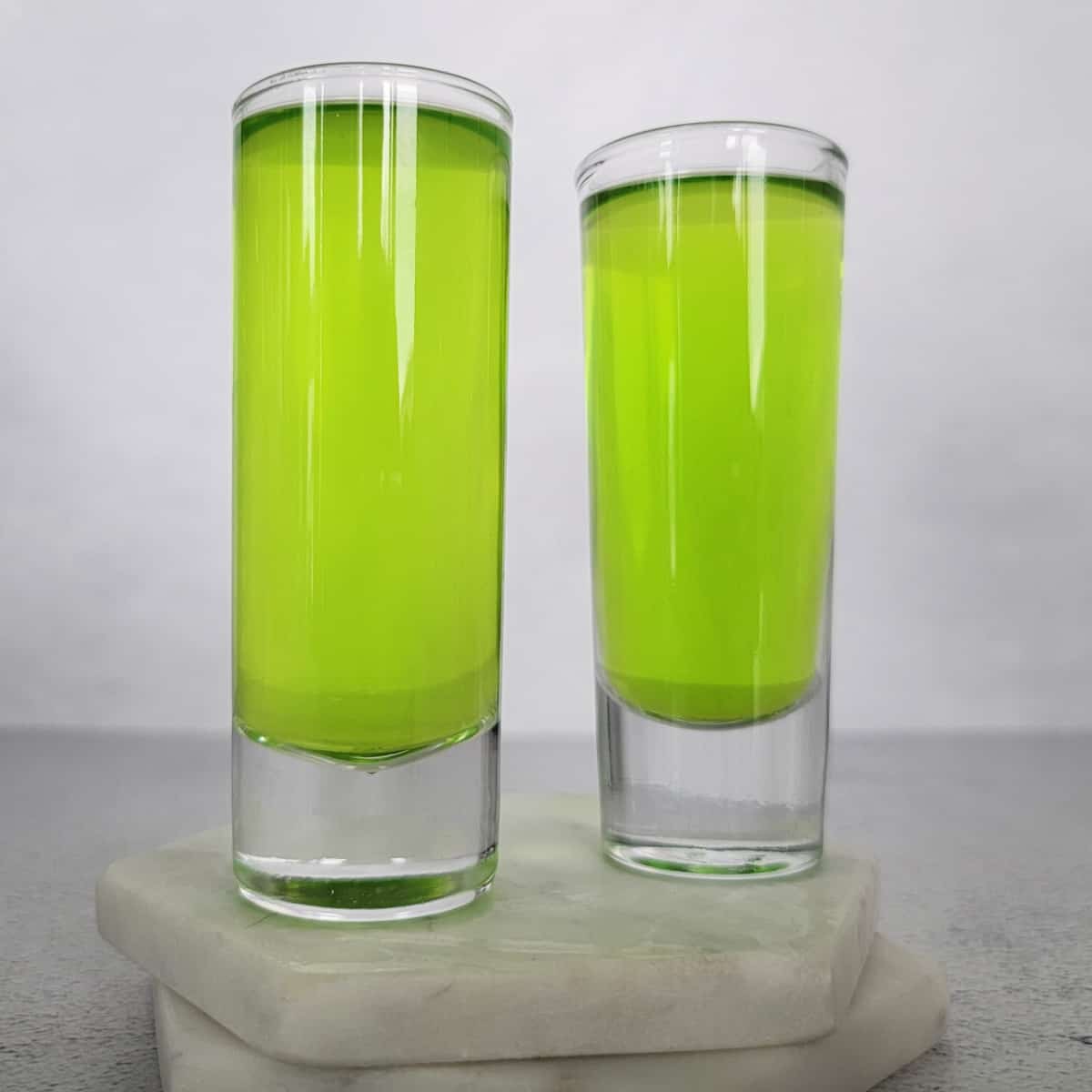 Two bright green ninja turtle shots on white coasters