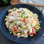 Orzo Pasta Salad on a blue plate next to a wooden spoon