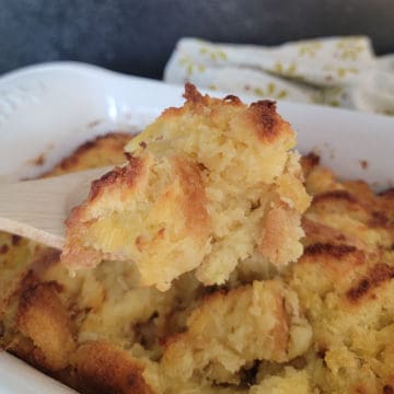 Pineapple Stuffing on a wooden spoon above a white casserole dish