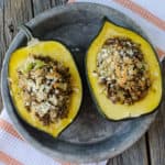 Sausage and rice stuffed acorn squash on a silver plate with a cloth napkin