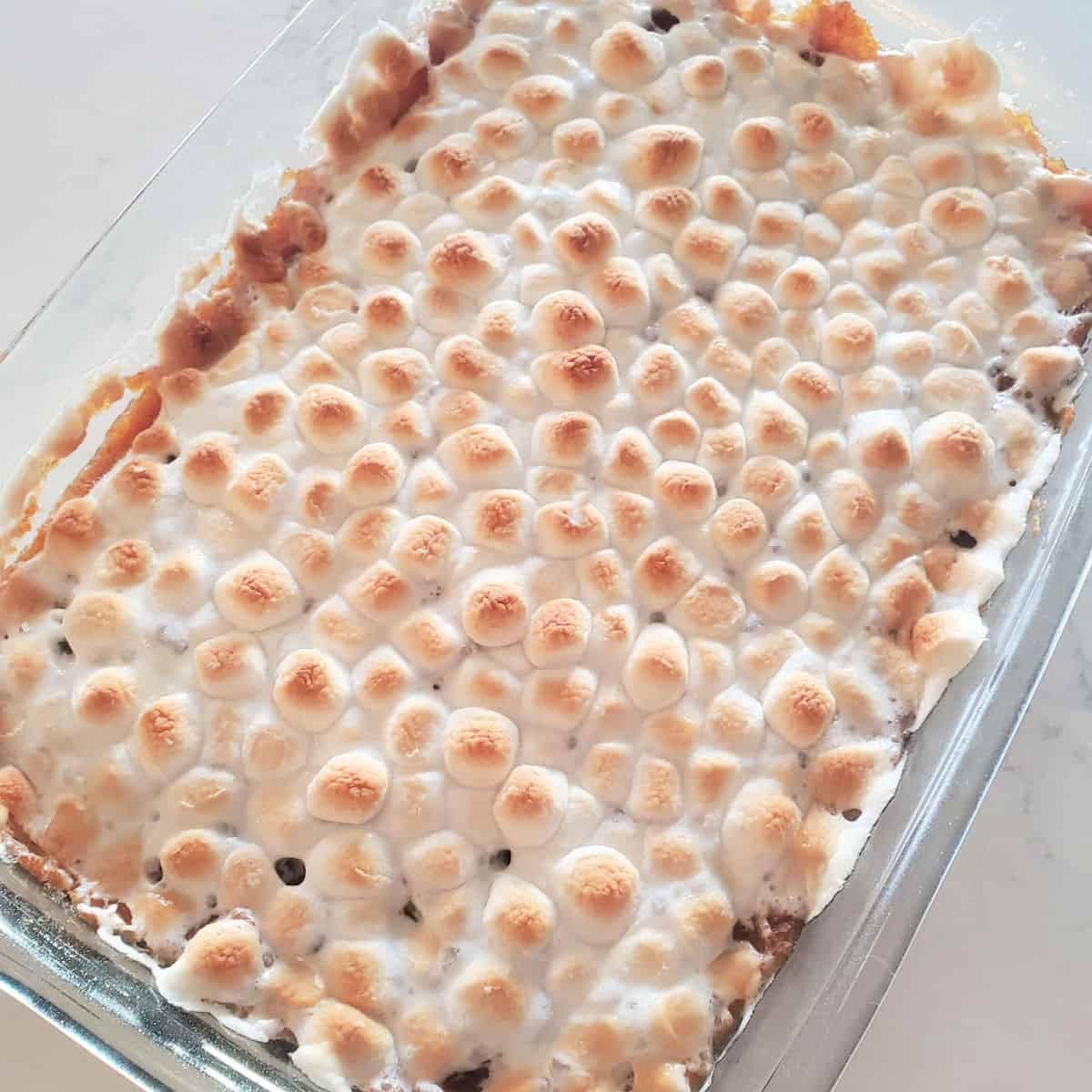 sweet potato casserole dopped with mini marshmallows in a glass casserole dish