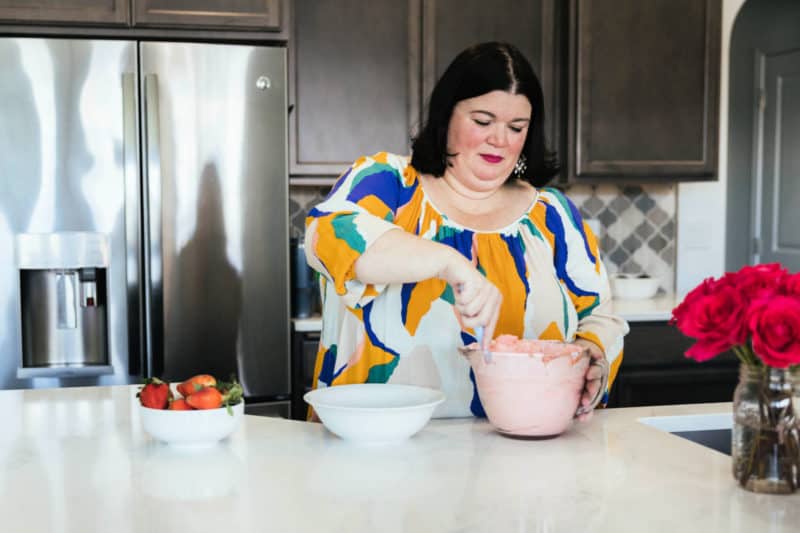 Tammilee stirring strawberry fluff salad in home kitchen 