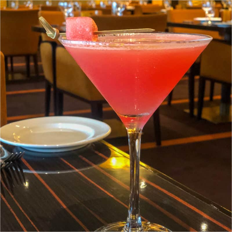 watermelon martini in a martini glass next to a white plate