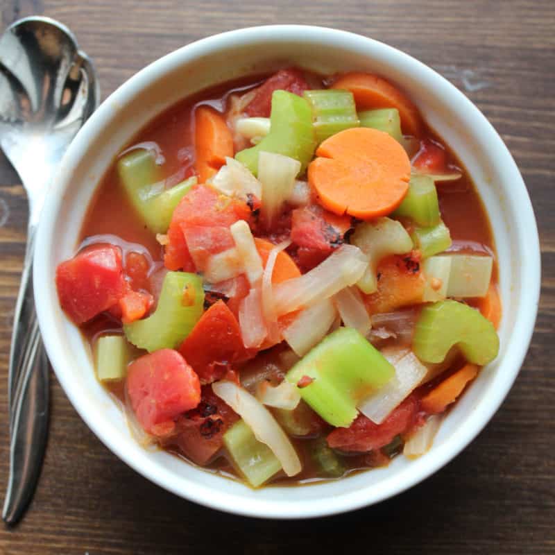 WW Vegetable Soup with carrots, celery, onions, tomato, in a white bowl next to a spoon