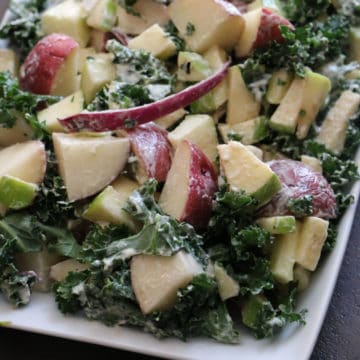 apple, kale, and potato salad on a white platter