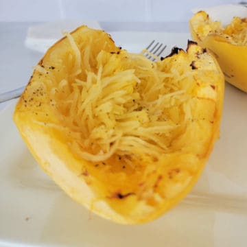 Spaghetti squash on a white plate next to a fork