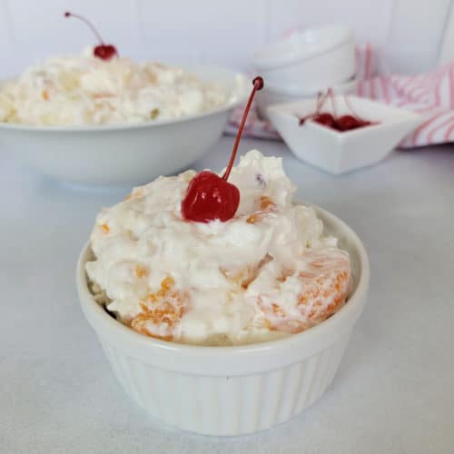 ambrosia salad with a maraschino cherry in a small ramekin.