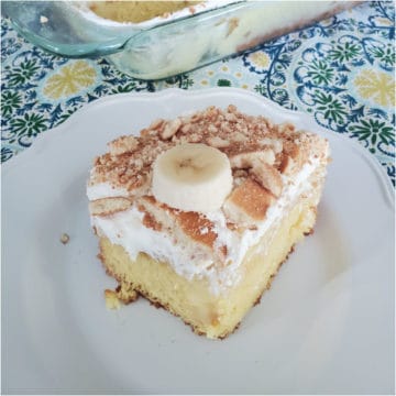 Slice of Banana Pudding Poke Cake on a white plate next to the cake dish