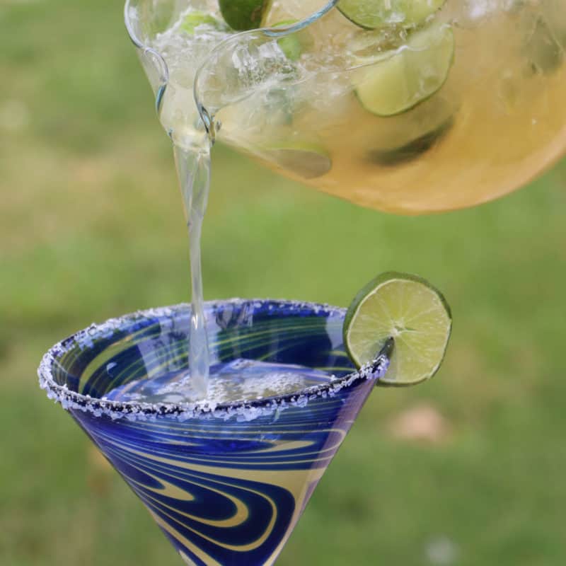 Beer Margaritas pouring from a glass pitcher into a margarita glass