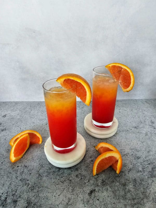 Best Vodka Sunrise Cocktails in tall glasses sitting on white coasters. 