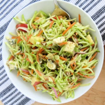 Broccoli slaw in a white bowl with a fork