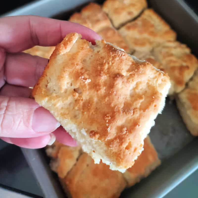 7 Up biscuit being held above a pan of biscuits