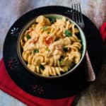 Mexican mac and cheese in a dark bowl next to a fork.