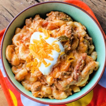 taco pasta topped with sour cream and cheddar cheese in a bowl