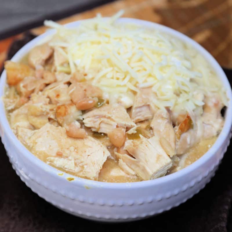 White chicken chili with garnished cheese in a white bowl