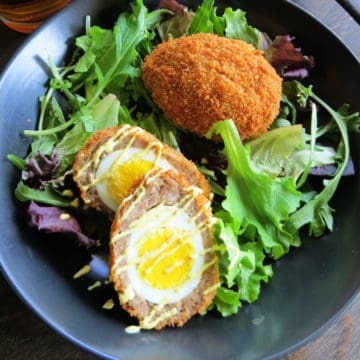 A pair of scotch eggs on a bed of lettuce