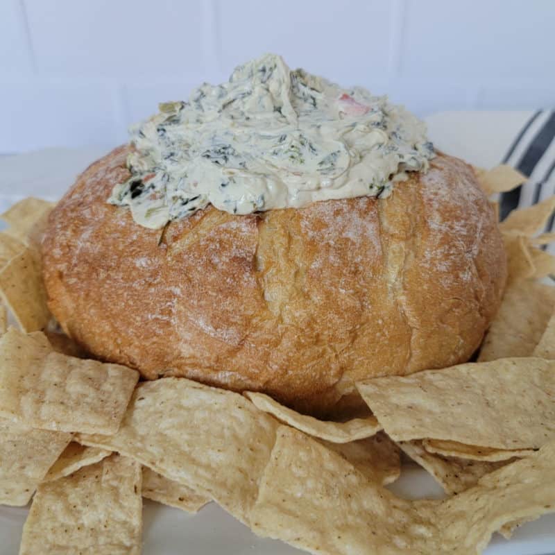 Creamy Knorr Spinach Dip in a bread bowl surrounded by tortilla chips