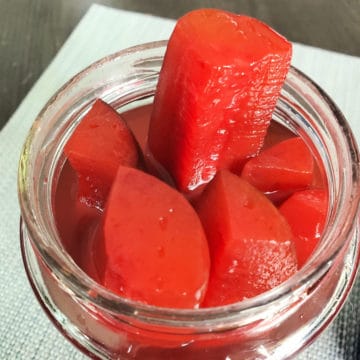 Cherry Kool Aid Pickles in a jar with one sticking out