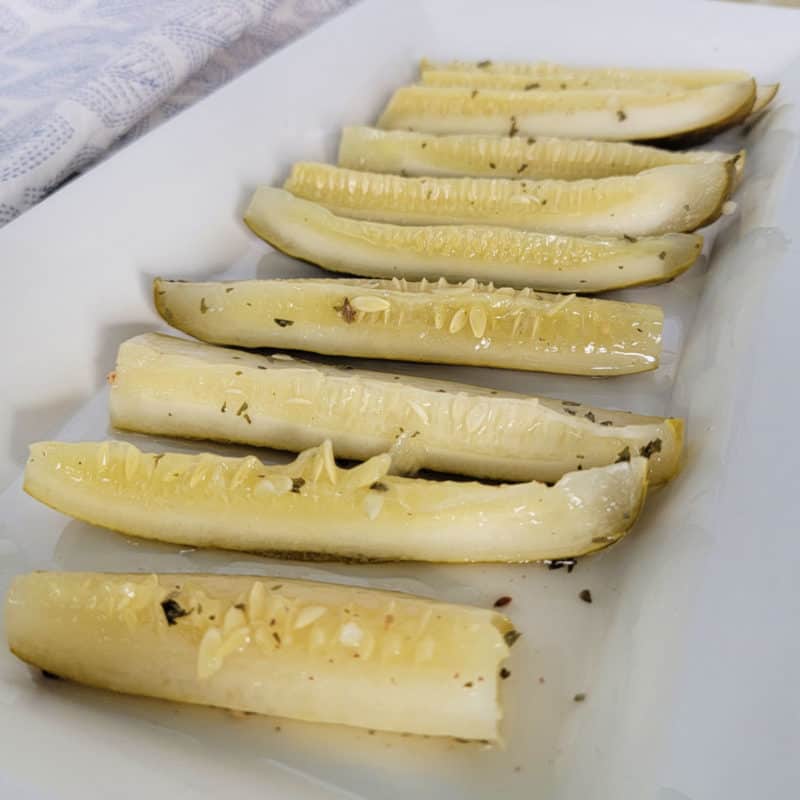 Ranch pickles lined up on a white platter with a napkin in the background