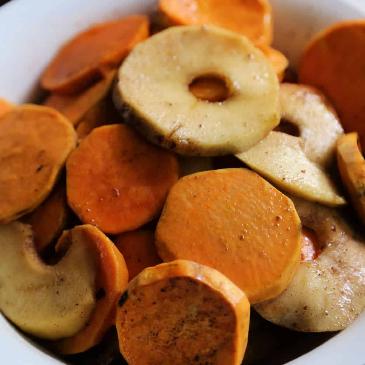 Slices of sweet potatoes and apples in a white bowl