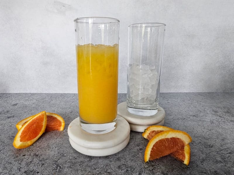 Orange Juice in a tall glass on a white coaster