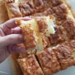 2 ingredient pineapple angel food cake cut into squares with one being held