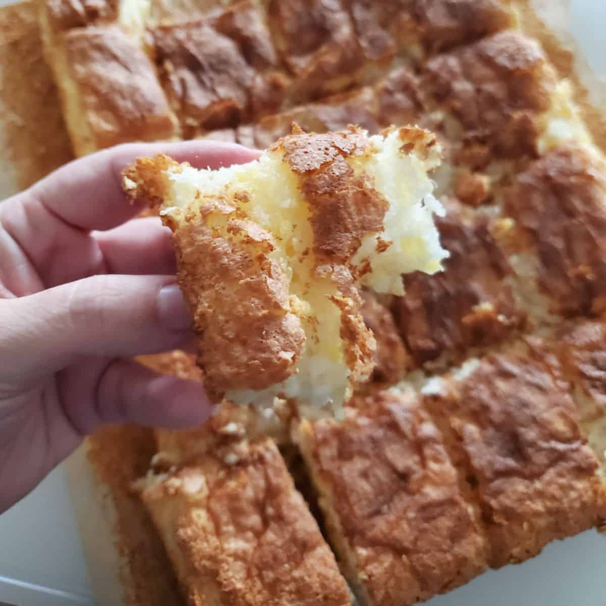 2 ingredient pineapple angel food cake cut into squares with one being held