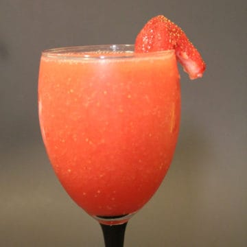 Coral Reef cocktail with a strawberry garnish in a champagne glass