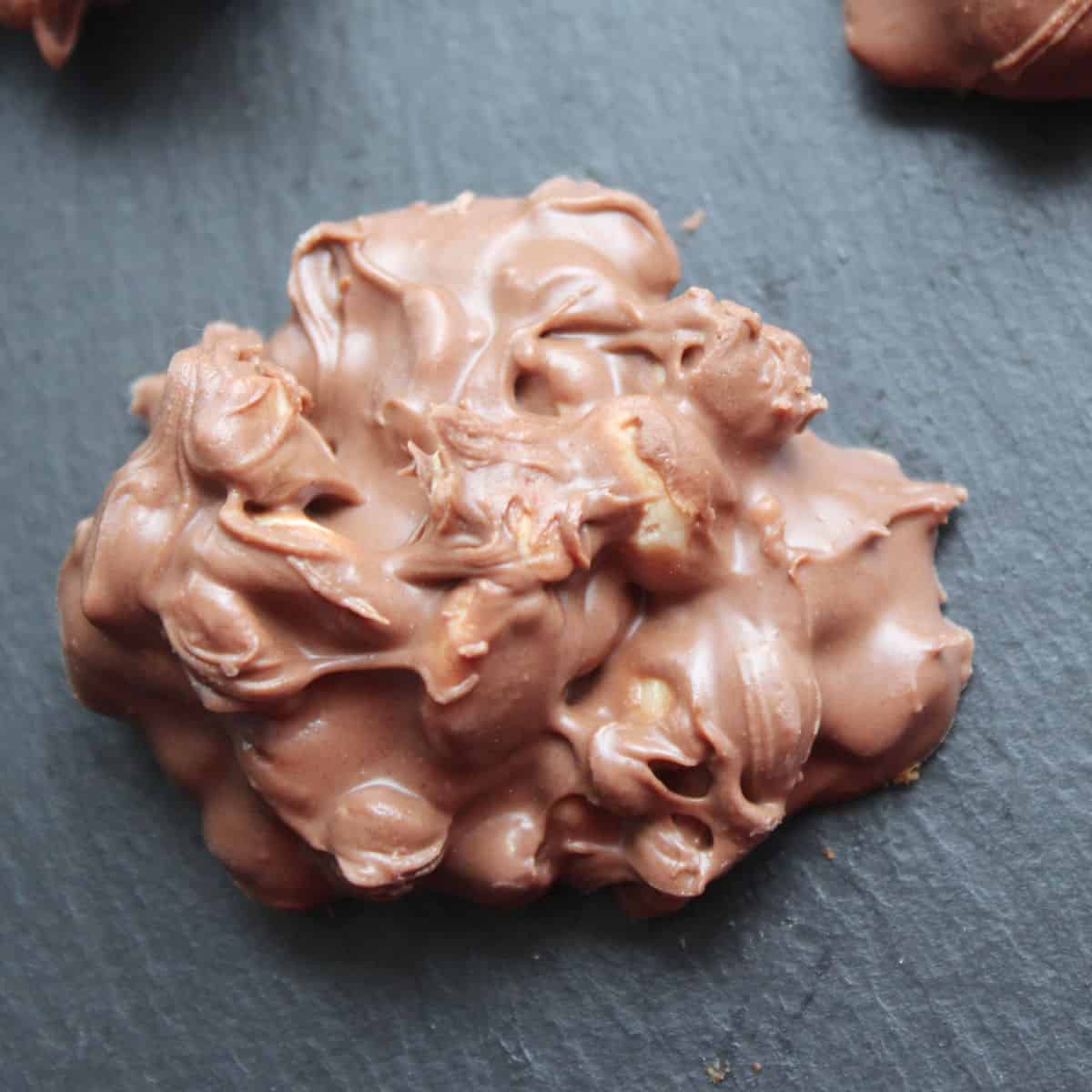 Crock Pot Chocolate Peanut Clusters on a slate board