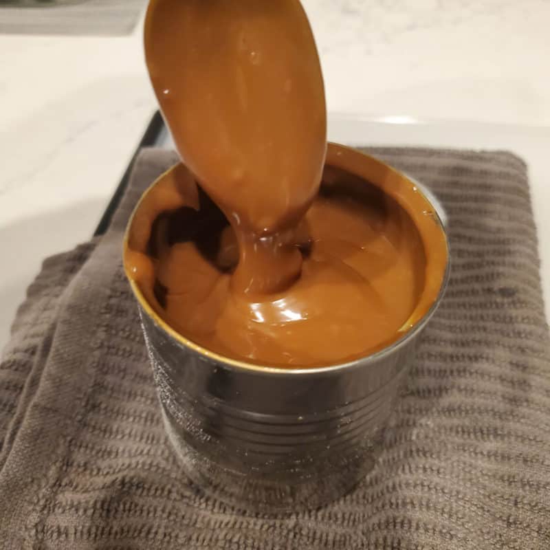 Spoon covered in caramel sauce coming out of a jar