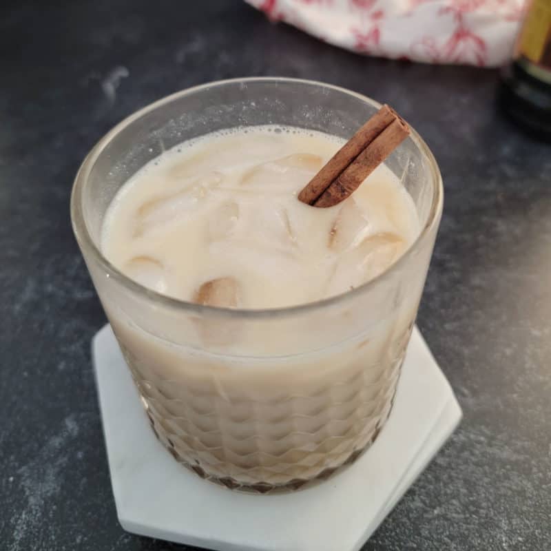 Eggnog White Russian in a glass with a cinnamon stick garnish