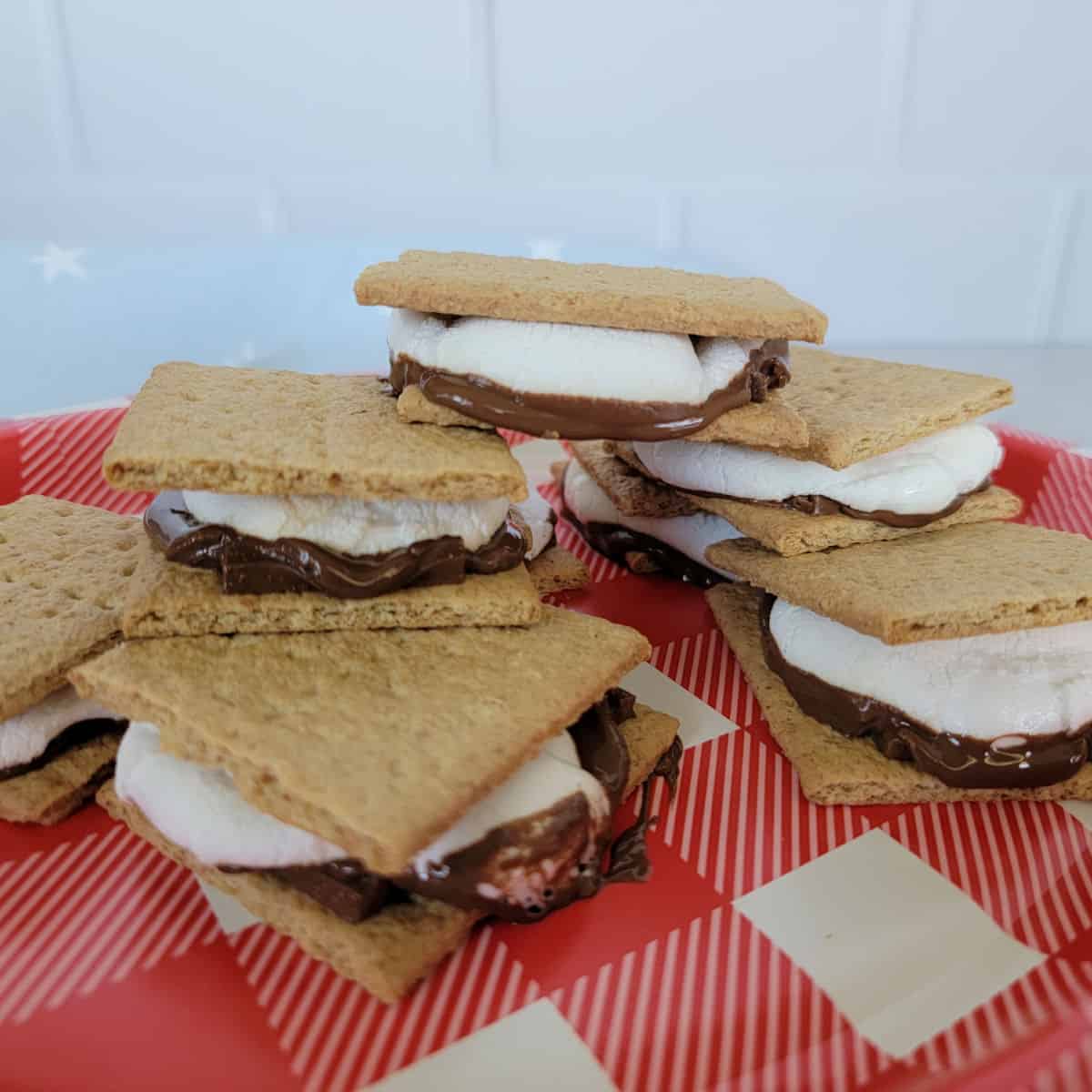 Stack of smores made in the oven on a red checked plate