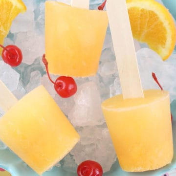 screwdriver popsicles on a bed of ice with maraschino cherries