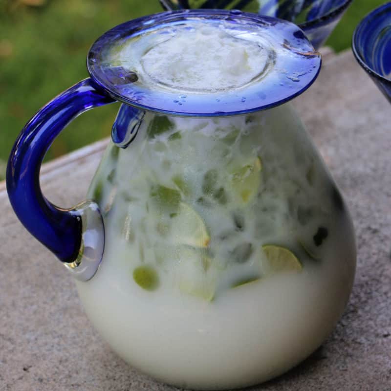 Brazillian Lemonade in a glass pitcher with limes