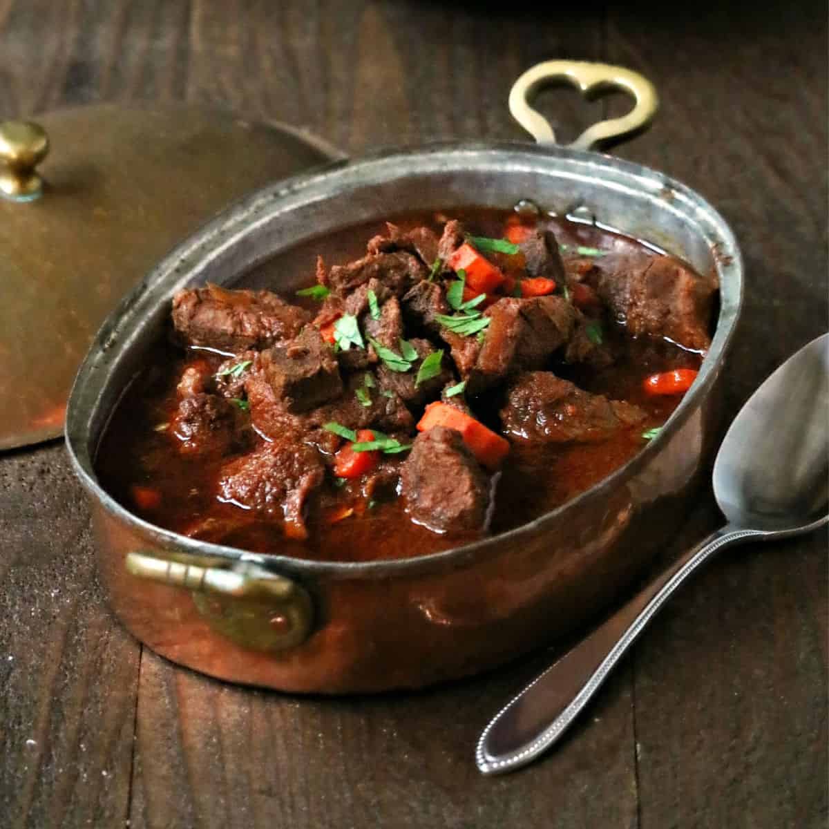 Hungarian Goulash in a metal pan next to a spoon and lid