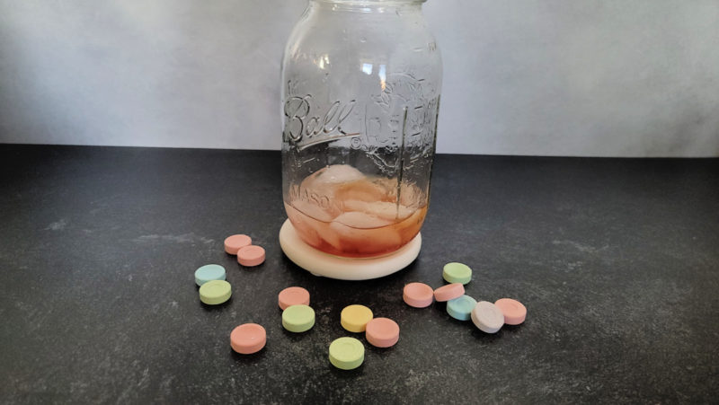 Red liquid and ice in a mason jar cocktail shaker surrounded by Sweet Tart candies 