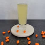 Orange Tic Tac Shot on a white coaster surrounded by orange tic tacs