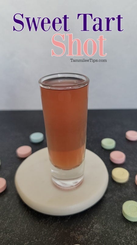 Sweet Tart Shot over a pink cocktail shot on a white coaster surrounded by sweet tart candies