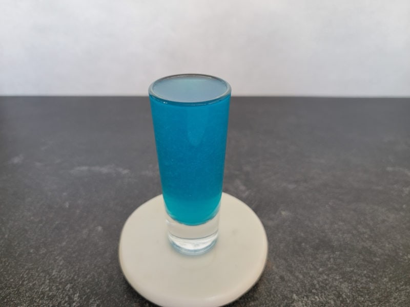 Blue cocktail shot on a white coaster