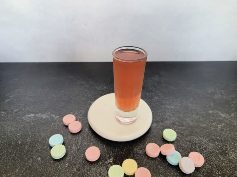 pink cocktail shot surrounded by Sweet Tart candy